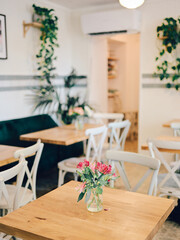 Cozy Café Interior with Wooden Tables and Greenery Adorned Walls in a Bright and Inviting Atmosphere