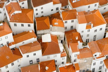 Aerial View of Residential Housing: An eye-level shot captures a picturesque community of homes with orange rooftops and white walls from an elevated perspective.