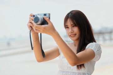 Woman capturing memories at the beach while enjoying a sunny day with a camera in hand