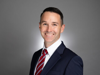 Portrait of white male professional in a blue suit and red tie. 