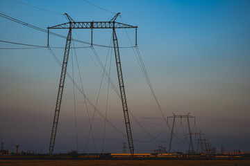 High voltage power line tower pole in a field at blue hour after sunset.