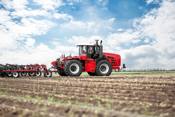 Obraz premium A red tractor is in a field of dirt