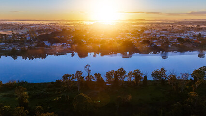 The river lies cold and blue as the golden sun rises across the landscape.