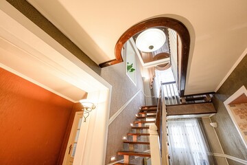Elegant interior featuring a staircase with wooden steps, arched doorway, and warm lighting,...