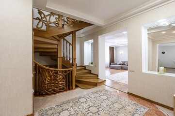 A luxurious interior with a wooden staircase, an elegant rug, and a glimpse of a living room with a...