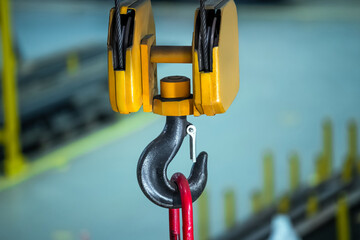 A yellow and black crane hook is hanging from a chain