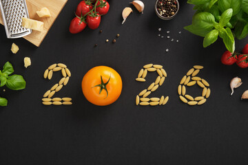 Numbers 2026 made of pasta and tomato on a dark stone background. A culinary idea for the new year.