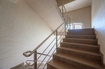 staircase with wooden steps and a sleek metal railing. The walls are off-white with a textured...