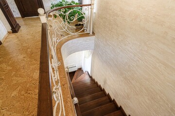 high-angle shot of a staircase with wooden steps and decorative wrought-iron railings, leading...
