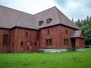 Obraz premium Side view of the wooden articular church in Svätý Kríž, Slovakia. Historic Lutheran church built from timber without nails, surrounded by green grass and trees.