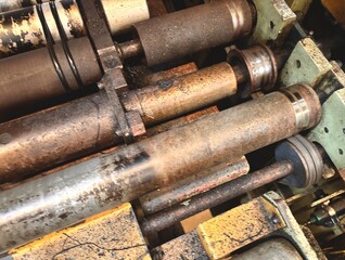 : A close-up view of heavily used, dirty industrial rollers and metal parts. The rollers show significant wear, rust, and residue, highlighting the rigorous environment of a heavy-duty factory or 