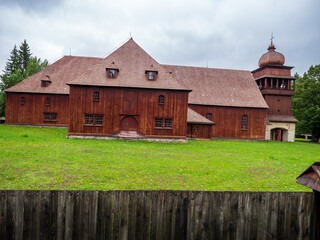 Fototapeta premium Wooden articular church in Svätý Kríž, Slovakia, surrounded by trees and fence. Historic Lutheran church built from timber in traditional style.