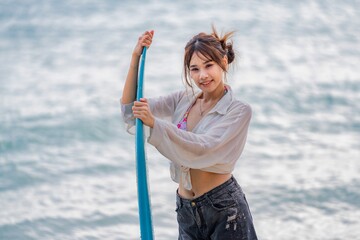 Young woman preparing to surf on the beach during warm daytime by the ocean shoreline