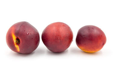 Three red ripe nectarines  on a white background close-up