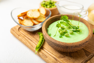 Green pea soup on a wooden table. Fresh pea soup bowl. Delicious healthy cream soup in a bowl with green peas and croutons. Healthy vegan puree. Copy space. Space for text.