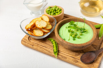 Green pea soup on a wooden table. Fresh pea soup bowl. Delicious healthy cream soup in a bowl with green peas and croutons. Healthy vegan puree. Copy space. Space for text.