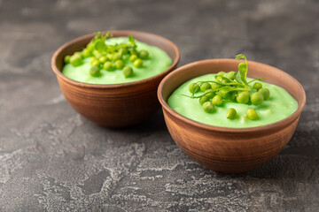 Green pea soup on a wooden table. Fresh pea soup bowl. Delicious healthy cream soup in a bowl with green peas and croutons. Healthy vegan puree. Copy space. Space for text.