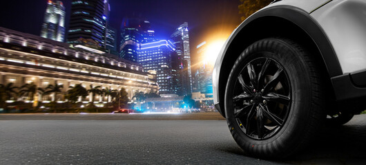 A black tire is shown on a city street at night