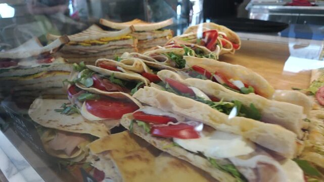 Italian bakery display with focaccia and pizza al taglio topped with tomatoes, pesto, and mozzarella, highlighting traditional street food and savory pastries