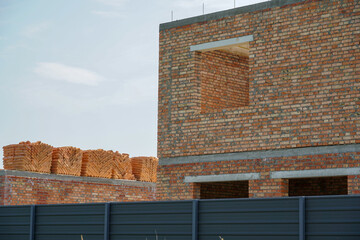Mustard plants flourish in the sunlight of an open field, adjacent to a half-constructed brick...