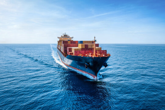 Aerial front view of a industrial container cargo ship traveling over the calm ocean
