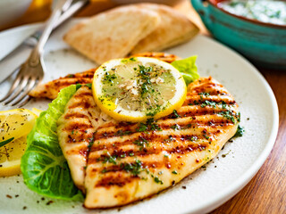 Grilled chicken breast with lemon on wooden table	