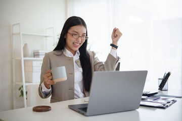 Excited businesswoman celebrating success while working on a laptop in the office.