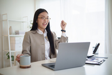Excited businesswoman celebrating success while working on a laptop in the office.