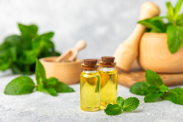 Essential oil mint on a wooden background. Peppermint essential oil with fresh mint leaves. A...