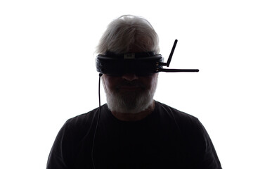 silhouette of bearded elderly man operating FPV drone in googles on his head, studio shot of man...