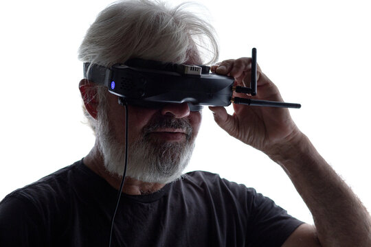 silhouette of bearded elderly man operating FPV drone in googles on his head, studio shot of man and modern technologies