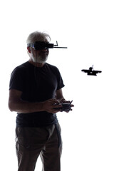 Silhouetted elderly man operating racing drone in goggles and remote control on a white isolated...