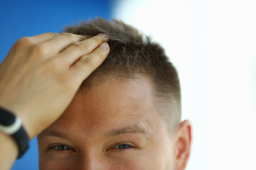 Smiling man playfully adjusts his hair while engaging with the camera in a brightly lit indoor space
