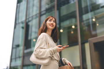 Fototapeta premium Single adult asian woman holding smartphone and shopping bag on black friday sale city people lifestyle