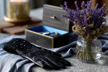 A beautifully crafted black glove adorned with beads rests next to a vintage jewelry box and a bouquet of dried flowers, creating a serene and artistic still life composition.