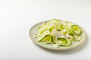 Cucumber salad on a wooden background.Homemade salad with fresh vegetables, cucumber, tomato, sweet pepper and lettuce in a plate.Vegetarian spring salad.Vegetarian diet.Healthy eating.Space for text
