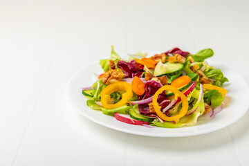 Cucumber salad on a wooden background.Homemade salad with fresh vegetables, cucumber, tomato, sweet pepper and lettuce in a plate.Vegetarian spring salad.Vegetarian diet.Healthy eating.Space for text