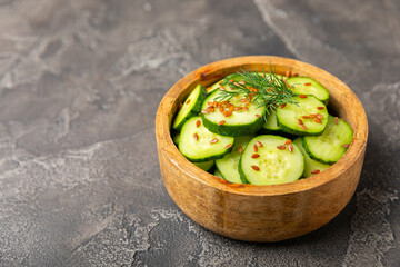 Cucumber salad on a wooden background.Homemade salad with fresh vegetables, cucumber, tomato, sweet pepper and lettuce in a plate.Vegetarian spring salad.Vegetarian diet.Healthy eating.Space for text