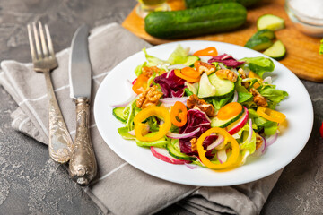 Cucumber salad on a wooden background.Homemade salad with fresh vegetables, cucumber, tomato, sweet pepper and lettuce in a plate.Vegetarian spring salad.Vegetarian diet.Healthy eating.Space for text
