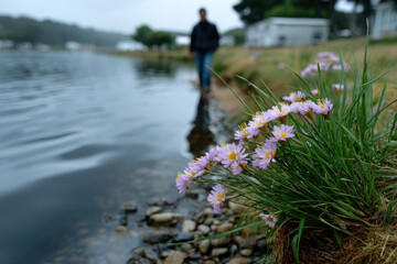 A picturesque lakeside scene featuring vibrant wildflowers in the foreground, with a figure walking along the water's edge amidst a serene, moody atmosphere.