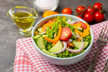 Cucumber salad on a wooden background.Homemade salad with fresh vegetables, cucumber, tomato, sweet pepper and lettuce in a plate.Vegetarian spring salad.Vegetarian diet.Healthy eating.Space for text