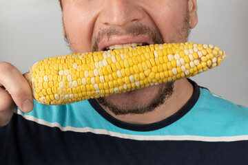 A young European man eating boiled corn
