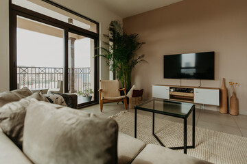 Fototapeta premium Chic living area with armchair, tropical plant and sunlight through tall windows