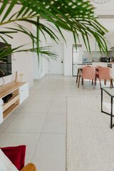 Chic living area with armchair, tropical plant and sunlight through tall windows