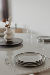 Elegant table setting with ceramic plates, wine glasses and minimal decor