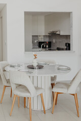 Elegant modern dining area with white round table and four chairs in bright room