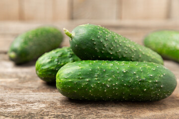 Cucumber on wooden background. Slice of cucumber on background. Fresh organic green cucumbers gherkin. Vegan. Salad ingredient. Farm vegetables. Cut vegetables with knife. Space for text. Copy space