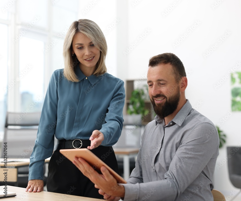 Poster smiling business partners working with tablet at table in office
