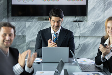 Confident CEO businessman in suit applauding during meeting in modern office, symbolizing teamwork, appreciation and professional success in corporate environment.