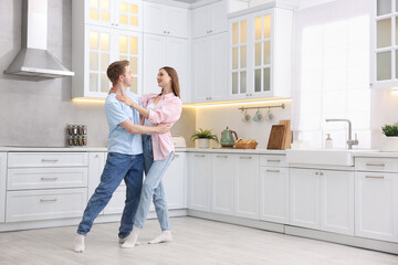 Happy young couple dancing together in kitchen